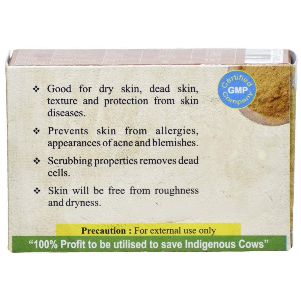 Back label of Nirmal Ganga bath scrubber detailing Ayurvedic benefits: helps alleviate dry, rough, and dead skin; protects against skin diseases, acne, allergies, and blemishes. Natural exfoliating properties leave skin soft and smooth. GMP-certified. Includes disclaimer “For external use only” and note about 100% profits supporting Indigenous cows.