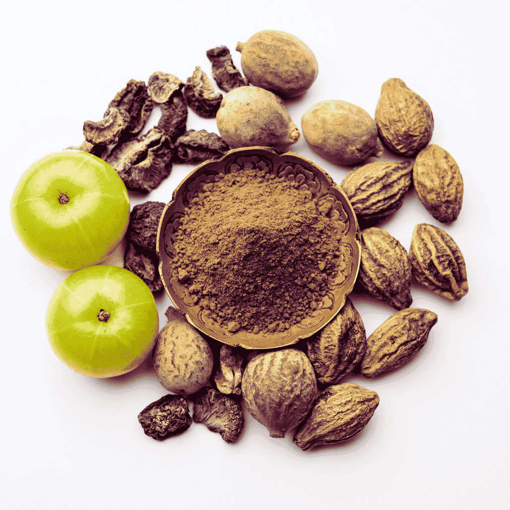 Triphala powder in a bowl with Triphala fruits surrounding it.