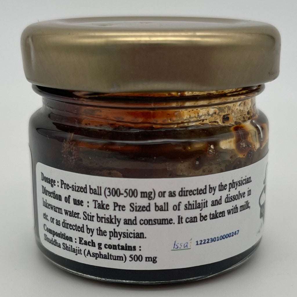 Close-up of Gavya Dhara Shilajit jar showing detailed label text. Highlights include dosage instructions (300–500 mg pre-sized ball), usage directions for mixing with lukewarm water or milk, and composition: 500 mg Shuddha Shilajit (Asphaltum) per gram. Presented as an Ayurvedic vitality supplement with physician guidance emphasis.