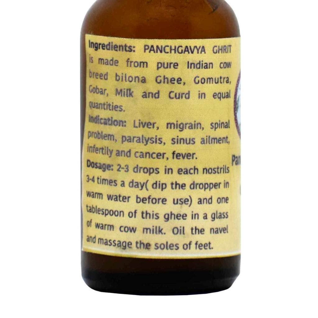 Close-up of a yellow product label on a brown glass bottle of Prakriti Panchagavya Nasal Drops. The label lists ingredients—bilona ghee, gomutra, gobar, milk, and curd from Indian cow—in equal quantities. Indications include liver issues, migraine, spinal problems, paralysis, sinus ailments, infertility, cancer, and fever. Dosage instructions: 2–3 drops in each nostril 3–4 times a day, dip dropper in warm water before use, and one tablespoon of ghee in warm cow milk; oil the navel and massage the soles.